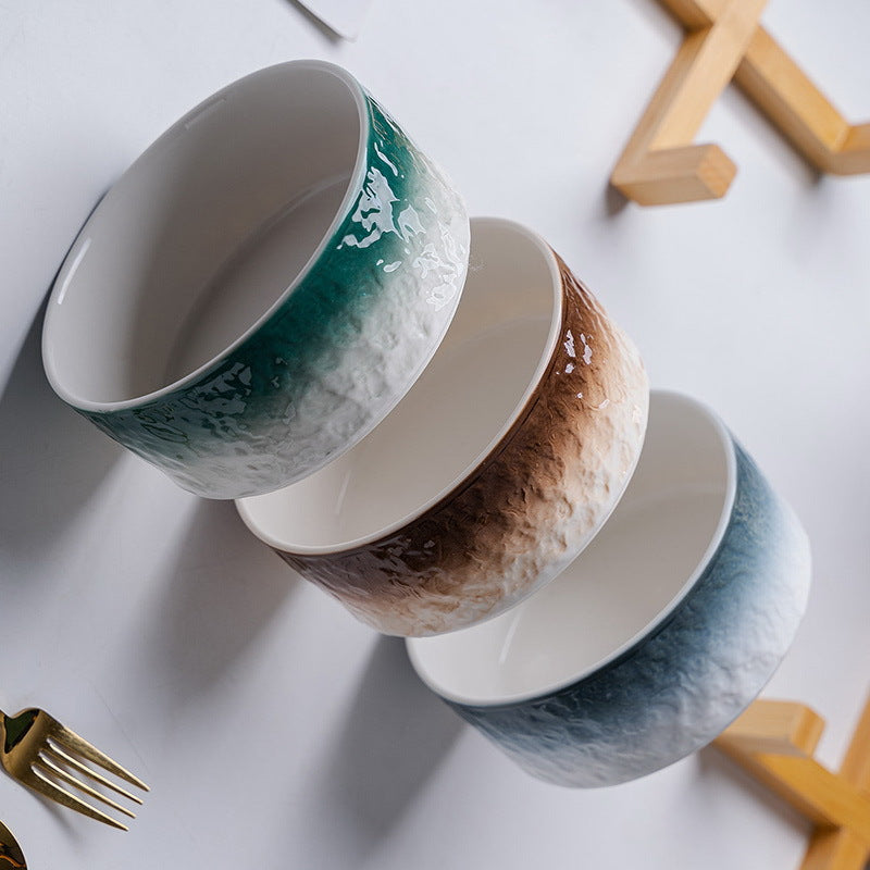 Vue d'ensemble de la collection de gamelles pour chat en porcelaine (vert, marron, orange, bleu, jaune) avec supports en bois naturel, design minimaliste sur table blanche, Palais Félin Paris.