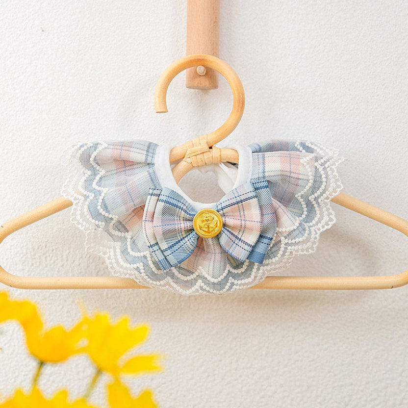  Présentation haute couture du collier pour chat bleu saphir avec son petit nœud papillon et sa perle, suspendu à un cintre élégant pour souligner sa finesse artisanale. Palais Félin Paris.
