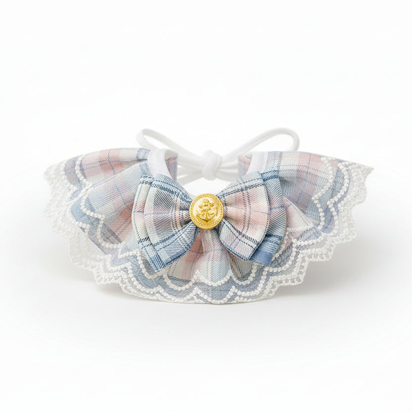 ​Collier d'exception pour chat en tissu bleu saphir, orné d'un petit nœud papillon artisanal, d'une perle de nacre et de détails dorés - Palais Félin Paris.