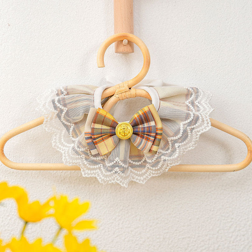Collier de prestige pour chat en tissu jaune impérial et noir, avec son petit nœud papillon et sa perle, présenté sur un cintre élégant style haute couture.
