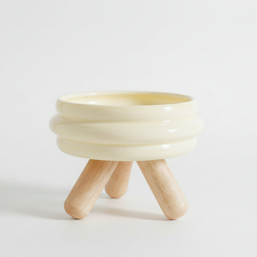 ​Gamelle individuelle au design vibrant pour chat en céramique jaune, posée sur un support minimaliste en bois de chêne clair croisé, isolée sur un fond blanc, signée Palais Félin Paris.
