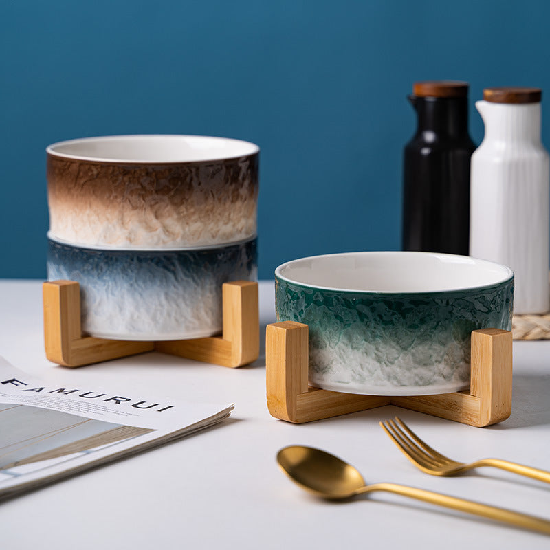 ​Gamelles pour chat haut de gamme en porcelaine bleue, marron et vert sur supports en bois naturel, présentées dans un décor de table élégant avec couverts dorés, Palais Félin Paris.